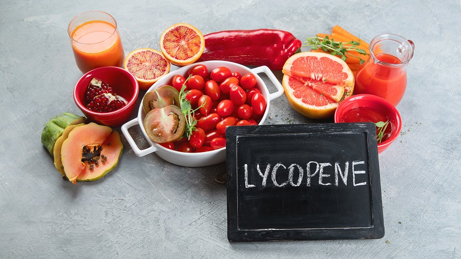 Pomidorki, cytrusy i soki oraz czarna tabliczka z napisem lycopene. 