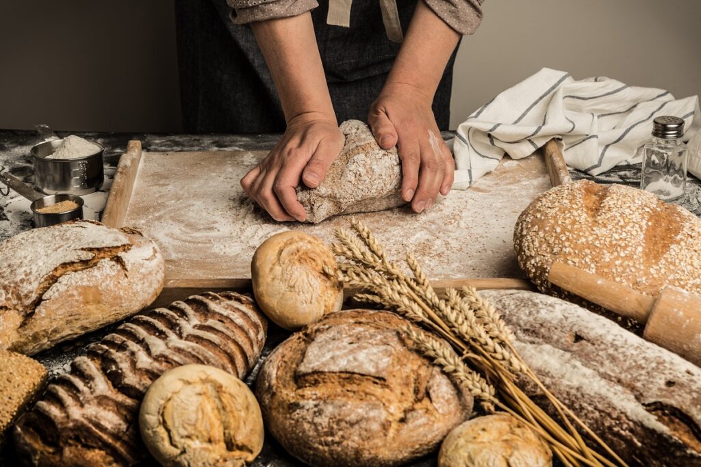 Dłonie wyrabiają chleb, wokół pieczywo