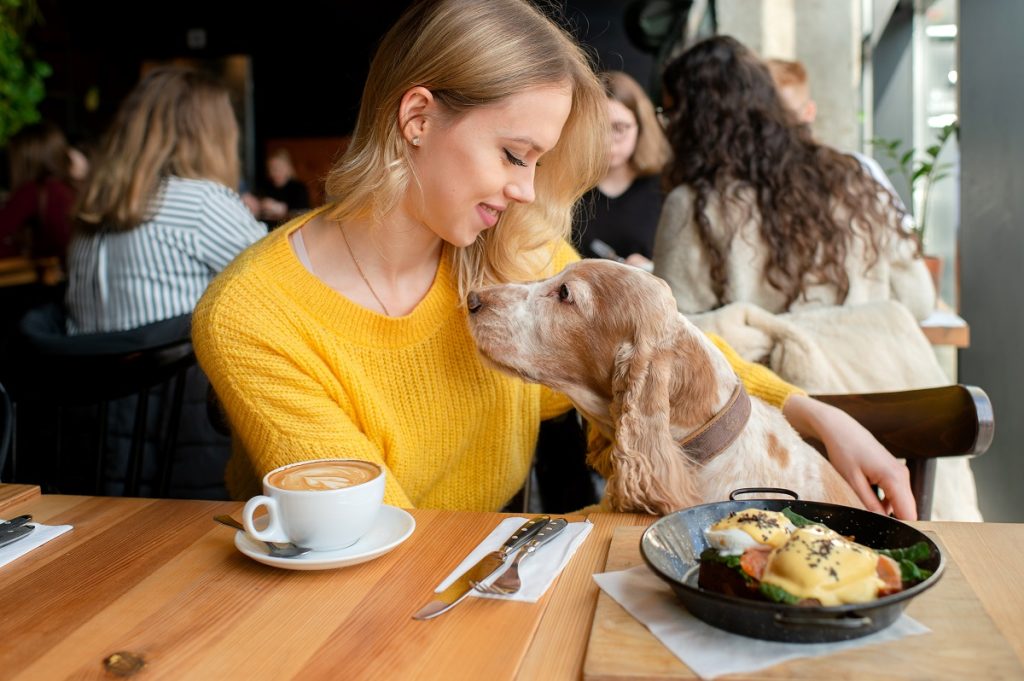 Kobieta i pies przy stole w restauracji.